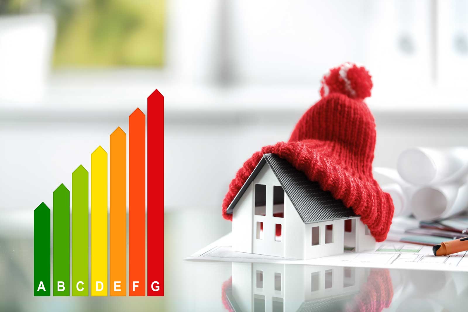 model of a house wearing a bright red bobble hat to represent the insulation properties of a green roof